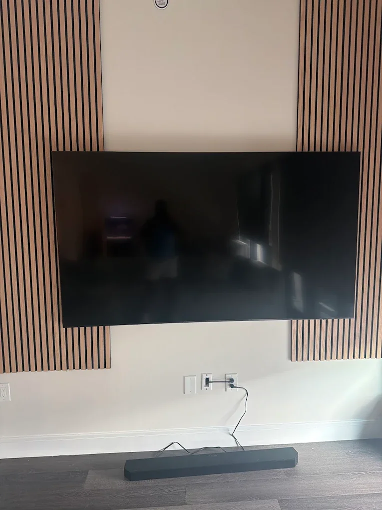 Large TV mounted across a wood slat accent wall by Assemble Pro NJ